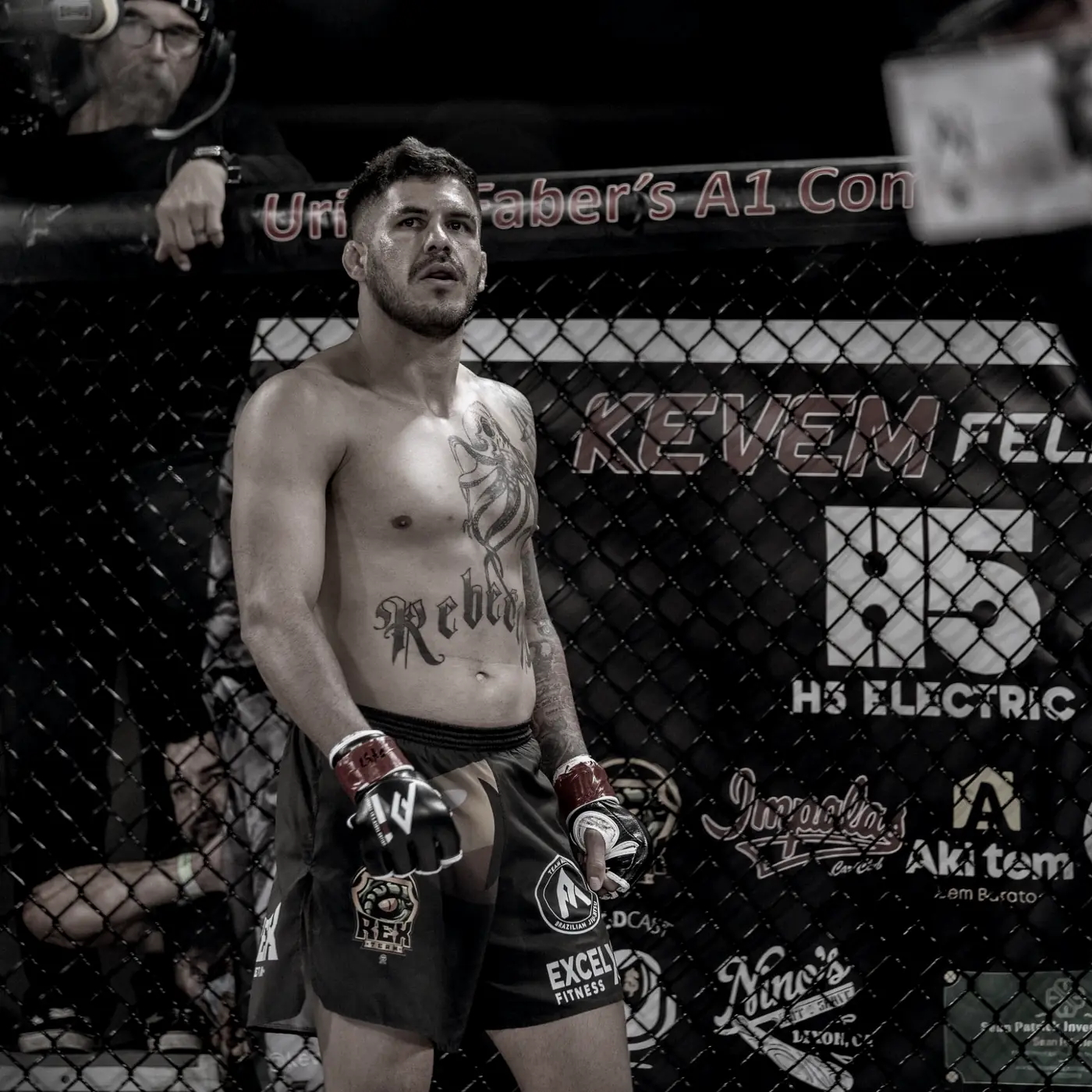 Kevem in the cage in front of the KEVEM FELIPE banner with partner brands