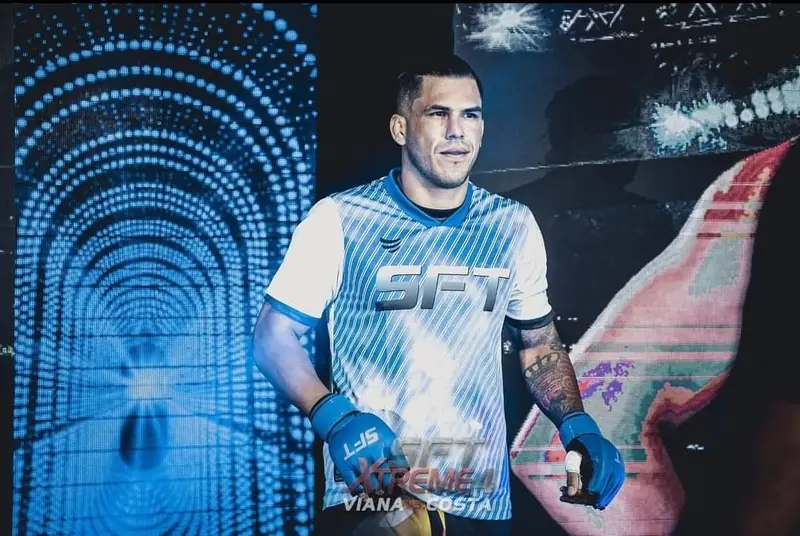 Kevem com a camisa do SFT diante de um telão de LED